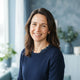 A friendly woman with a warm smile posing for a professional headshot in a bright, modern setting.
